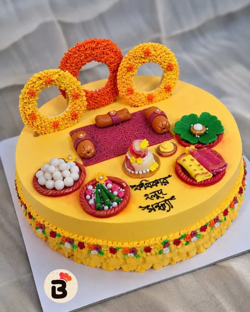 হলুদ বাটারক্রিমের গায়ে হলুদের কেক — উপরে ফুলের ছাউনির নিচে হাতে আঁকা বর-কনে, চারপাশে হলুদের সাজে সাজানো কাপকেক